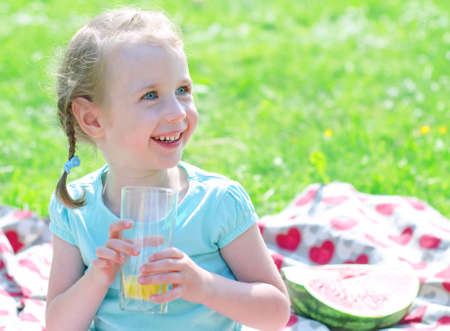 Portrait of smiling girl drinking orange juice in th parkの写真素材