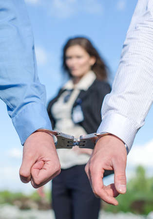 Close up view of hands in handcuffs and female FBI agent on backgroundの写真素材