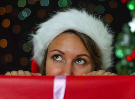 Attractive woman hiding behind a christmas gift.の写真素材