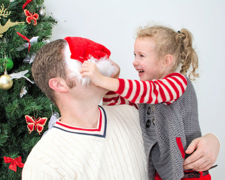Father and daughter having fun at the christmas   Girl trying to put on Santaの写真素材
