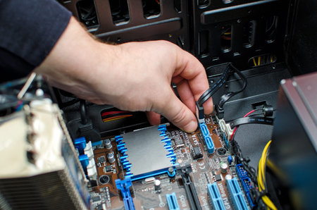 Hands of technician installing HDD on motherboard
