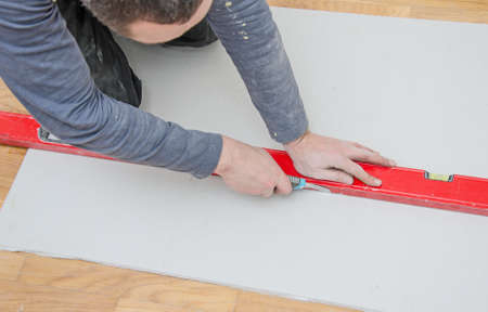 Man measuring and cutting gypsum plasterboardの写真素材
