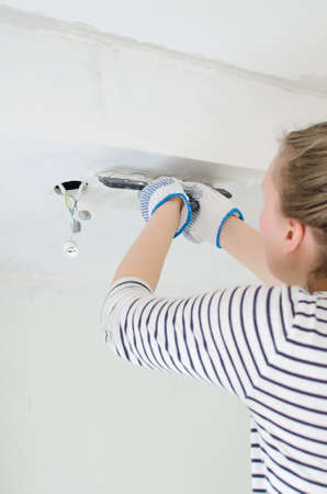 Female worker repairs gypsum plasterboard frame with spackling pasteの写真素材