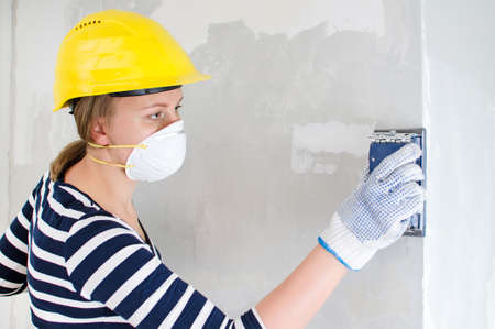 Female plasterer in hard hat polishing the wall.の写真素材