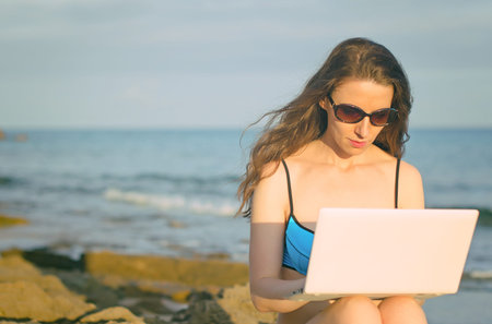Woman with laptop working on the beach  Place for text の写真素材