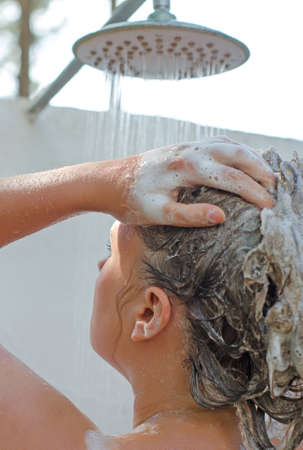 Woman having shower outdoors  View from the back の写真素材