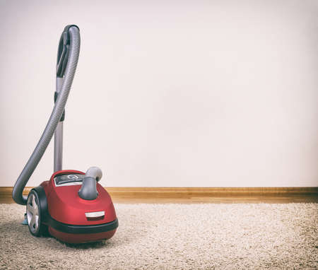Red vacuum cleaner in empty room. Photo with vignette.の写真素材