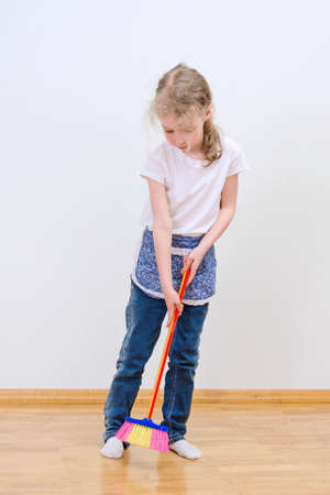 Little cute girl brooming floor at home.の写真素材