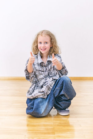 Smiling little girl in oversized jeans and shirt.の写真素材