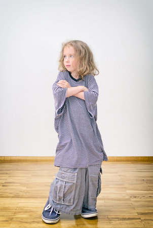 Little girl posing in oversized shorts and shirt.