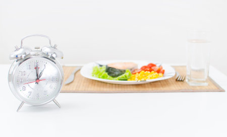 Alarm clock and lunch or dinner on background 