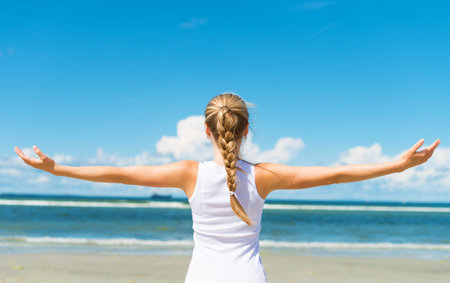 Pigtailed girl on the beach. View from the back.
