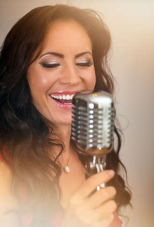 Attractive brunette woman singing into vintage microphone.の写真素材