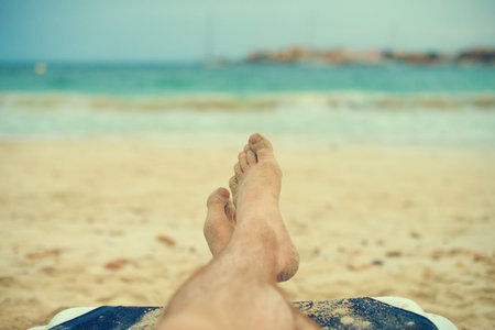 Man sunbathing on lounger. Legs. Vintage effect.
