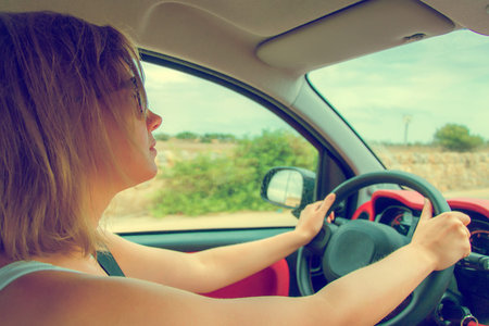 Woman in glasses driving car. Vintage effect photo.