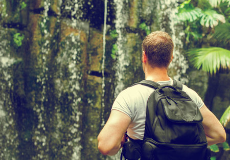Tourist with backpack near waterfall. Vintage effect. Space for your text.