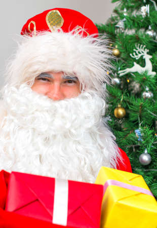 Santa Claus with gifts near the Christmas tree.の写真素材