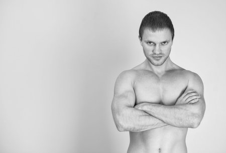 Muscular male model with arms folded. Black and white. Place for text.の写真素材