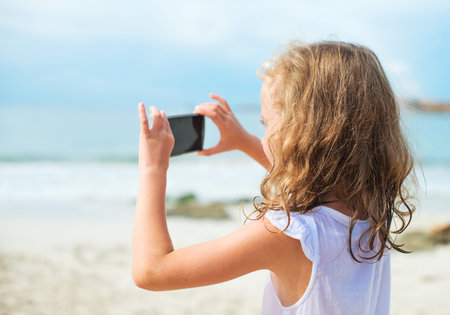 Little girl making video or photo with mobile phone.
