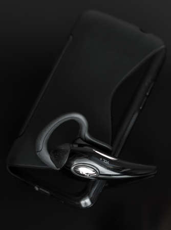 Close-up of handsfree bluetooth device near mobile phone.の写真素材