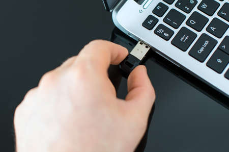 Hand plugging usb flash drive to laptop.の写真素材