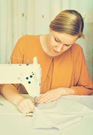 Woman working on sewing machine in the factory. Vintage effect.の写真素材