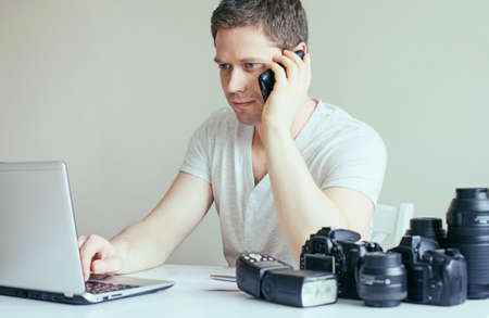 Photographer discussing photos with client by mobile phone.の写真素材