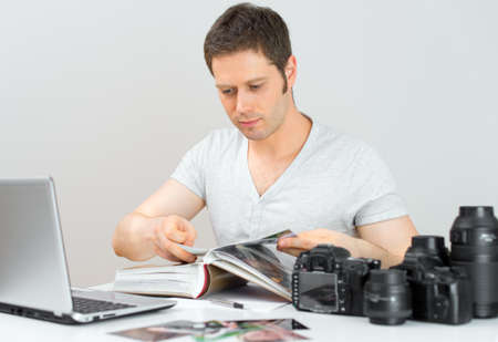 Male photographer watching photo album at his workplace.の写真素材
