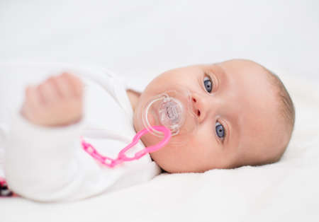 Newborn little baby with dummy on the bed.の写真素材