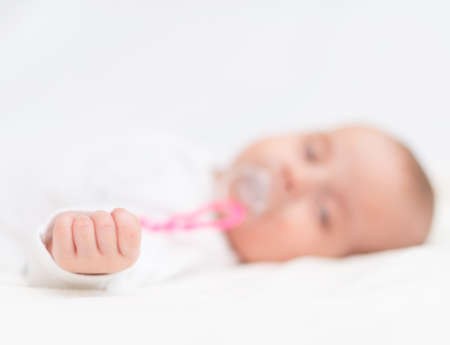 Newborn little baby with dummy sleeping on the bed.の写真素材