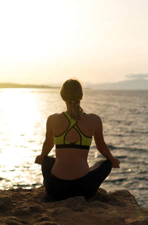Young woman practicing yoga near the sea.の写真素材
