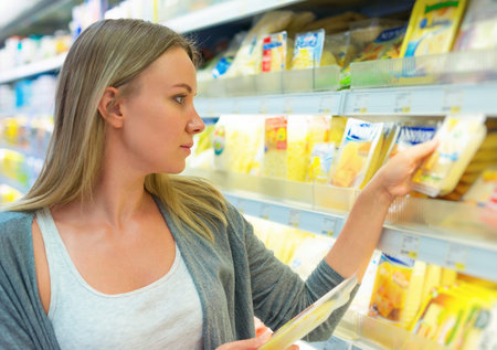 Woman choosing cheese in grocery store.の写真素材