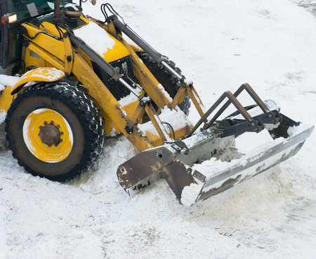 Tractor shoveling snow on the street.