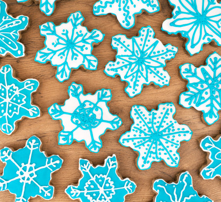 Many snowflake shaped cookies on the wooden table top.