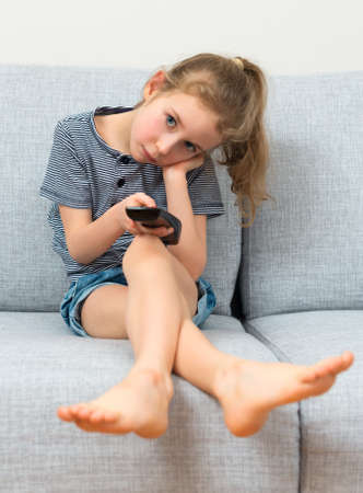 Little girl looking very boring programs on TV.の写真素材