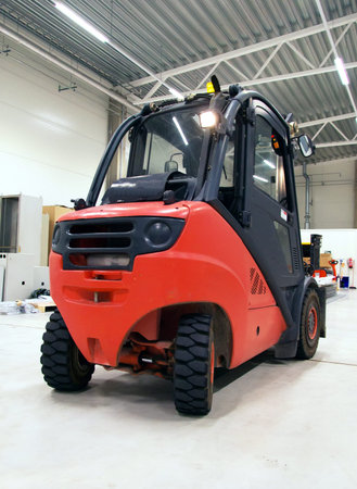 Orange forklift loader in the modern warehouse.