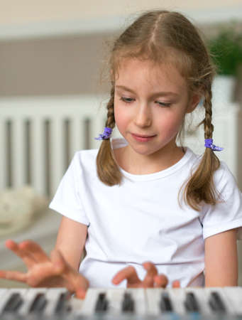Cute little girl learning to play the piano.の写真素材