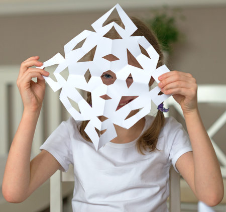 Little girl showing snowflake made of paper.の写真素材