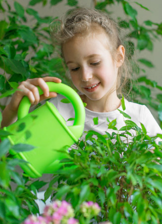 Cute little girl watering flowers at home.の写真素材