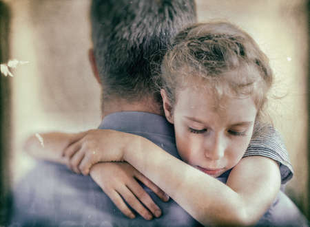 Sad little girl hugging his dad. Vintage effect.の写真素材