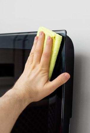 Man's hand wipes dust from TV panel.