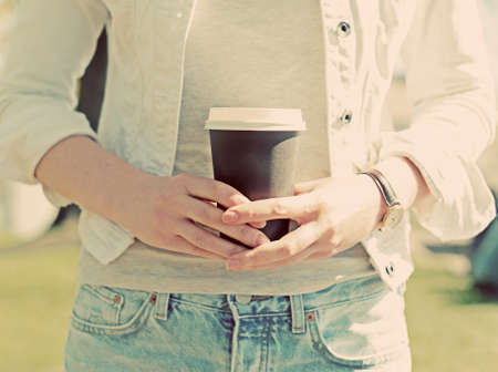 Woman's hands holding coffee cup outdoors.の写真素材