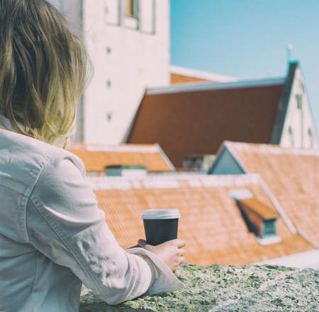 Woman holding coffee cup in the city.の写真素材