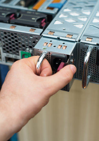 Computer technician installing power supply unit on server.
