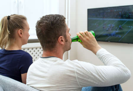 Couple watching American football on tv.の写真素材