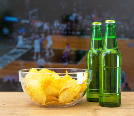 Beer and chips in front of TV with basketball match.の写真素材