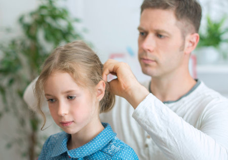 Father combing her daughter at home.の写真素材