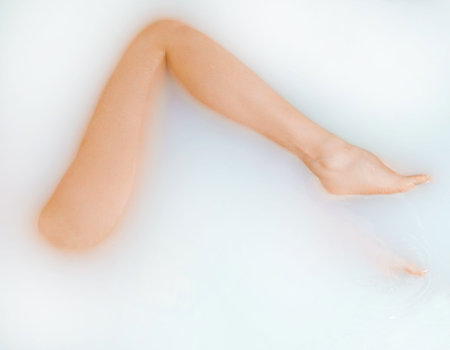 Beautiful woman legs in bath with milk. SPA treatments for skin care.