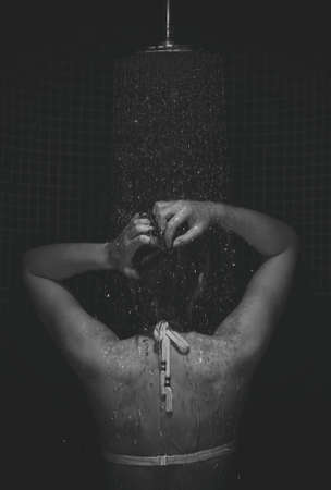 Young woman enjoying in the shower. Back View. Black and white photo.の写真素材