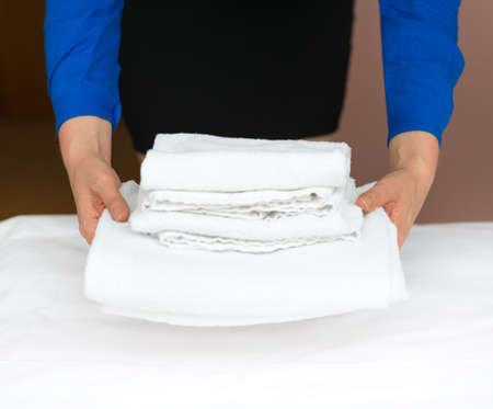 Room service. Woman changing towels in hotel room.の写真素材